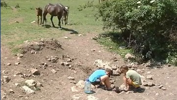 Селяне набирают воду из источника, вокруг которого пасутся животные. Кадр из видео.